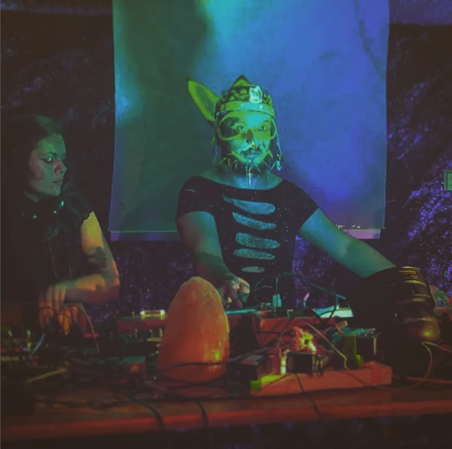 Hyperlord Kynikos in a mask behind his synths
